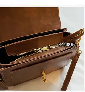 Detail view of double-layer interior structure and gold zippers on brown leather bag