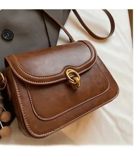 Detailed side view of brown vintage satchel with gold twist lock and fur pompom charm