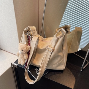 Chic beige PU leather crossbody dumpling bag with cute bear charm and wide strap