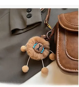 Chic brown fluffy animal charm with cord legs hanging on a luxury leather crossbody bag