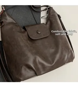 Detail of dark brown vintage leather tote featuring soft texture and silver hardware