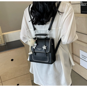 Detail of black PU leather backpack with star buckle and plush charm on white shirt