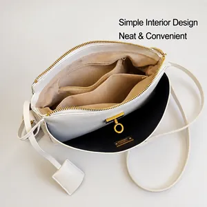 Detail view of white crossbody bag interior with multiple compartments and gold buckle
