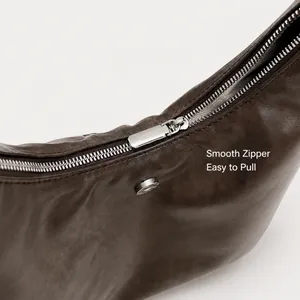Detail of smooth silver zipper and magnetic clasp on dark brown leather tote bag