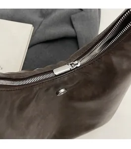 Detail of smooth silver zipper and magnetic clasp on dark brown leather tote bag