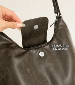 Detail shot of the secure magnetic snap closure on a vintage brown leather tote bag