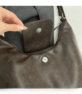 Detail shot of the secure magnetic snap closure on a vintage brown leather tote bag