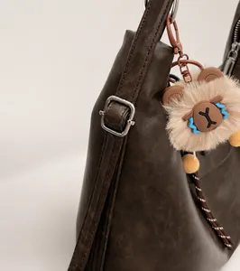 Detail of silver metal buckle on brown leather tote bag with unique plush toy pendant