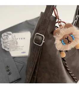 Detail of silver metal buckle on brown leather tote bag with unique plush toy pendant