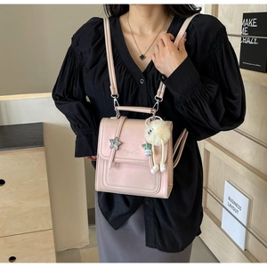 Detail of pink PU leather small square bag with star buckle and plush ball accessory