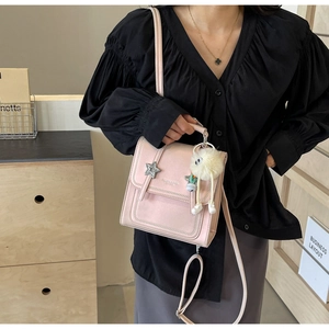 Detail of a pink square crossbody bag with star clasp and white plush monster charm