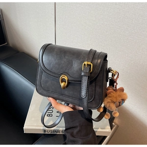 Detail of vintage grey crossbody bag with gold oval lock and cute plush lion charm