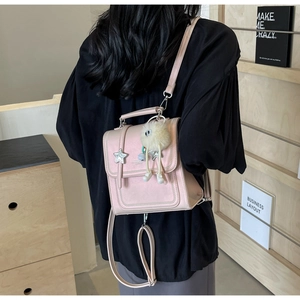Detail of pink mini backpack with star studs and plush pendant worn by a model