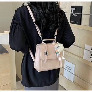 Pink mini backpack with silver star detail and fluffy charm shown on a female model