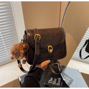 Detail of vintage brown matte leather crossbody bag with gold buckle and plush charm