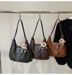 Detail of hobo tote bag in black, dark coffee and caramel with plush lion pendant