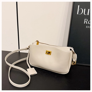 Detail of premium cream white handbag with golden square metal twist lock on black surface