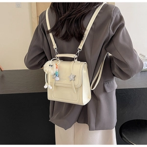 Rear view of model wearing a creamy white mini backpack with star charms and plush toy