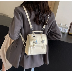 Mini cream faux leather backpack detail featuring cute plush charms and star pendant