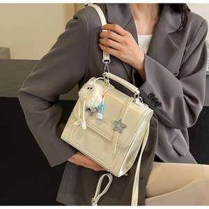 Detail of cream white leather crossbody bag with metal star studs and plush pendant charm