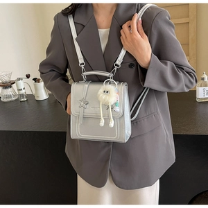 Silver metallic mini backpack with star stitching and plush charm shown on model