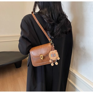 Brown retro leather crossbody bag detail with golden lock and plush lion charm accent