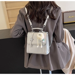 Silver metallic backpack with cute doll charm shown as worn on model's back in daily style