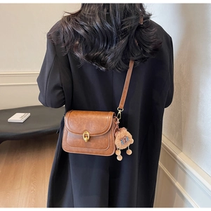 Brown vintage leather shoulder bag with gold twist lock and a cute plush animal charm