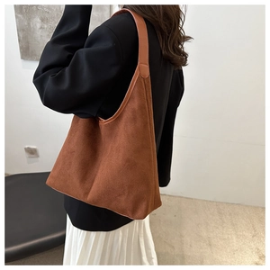 Dettaglio della borsa tote grande in pelle scamosciata marrone con bordi rinforzati e tracolla
