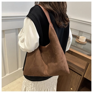 Detail view of a large brown suede hobo bag with high quality soft texture on a model