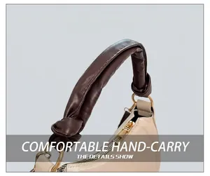 Detail show of beige crescent bag with brown ruched handle and golden metal ring