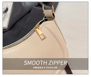 Close-up of smooth gold-tone zipper and beige faux leather on stylish crescent bag