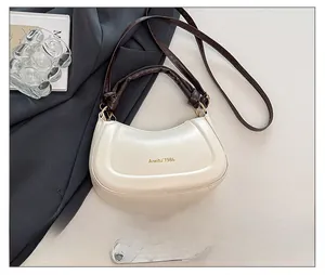 Close-up of cream leather hobo bag with gold logo and brown straps on a grey background