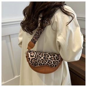 Detailed view of leopard print saddle bag with wide strap and gold hardware on model