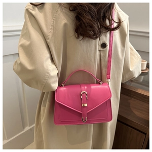 Detail shot of bright pink crossbody box bag with gold metal buckle and leather strap
