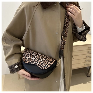 Detail of trendy leopard print saddle bag with wide shoulder strap and gold hardware