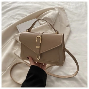 Detailweergave van kaki crossbodytas met gouden gesp op stijlvolle blazer achtergrond