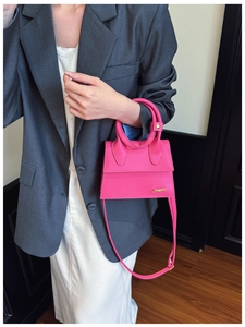 Détail du sac à main en cuir fuchsia avec poignée ronde et plaque logo métallique