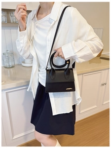 Détail d'un mini sac à main noir élégant avec poignée ronde et logo en métal doré