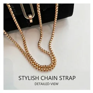 Close-up of luxury gold box chain strap with polished metallic buckle on denim bag