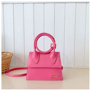 Détail du mini sac fuchsia en cuir avec logo doré et grande poignée anneau en métal