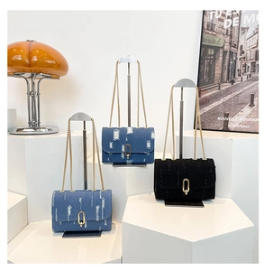 Close-up of denim shoulder bags with golden U-shaped hardware and chain straps