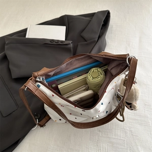 Grande borsa tote retrò con motivo a cuore e manici in pelle marrone su abito grigio