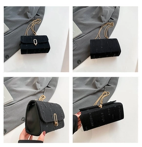 Detail of denim crossbody bag showing gold chain strap and oval metallic buckle