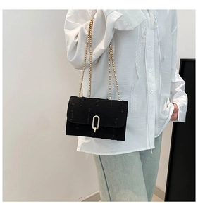 Close-up of black tweed small square bag with golden chain and U-shaped metal buckle