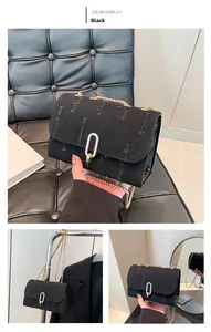 Detail of black denim crossbody bag with gold chain strap and U-shaped buckle closure