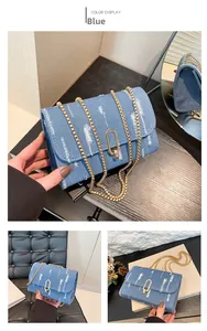 Detail of blue denim crossbody bag featuring distressed fringe and gold chain strap