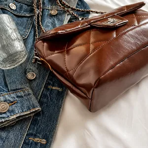 Détail du sac matelassé marron avec fermoir métallique sur fond de jean