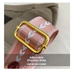 Close-up of pink woven adjustable strap with white heart patterns and gold metal buckle