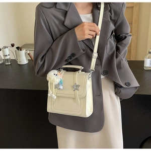 Detail of cream PU leather crossbody bag with star pendant and plush cartoon charm